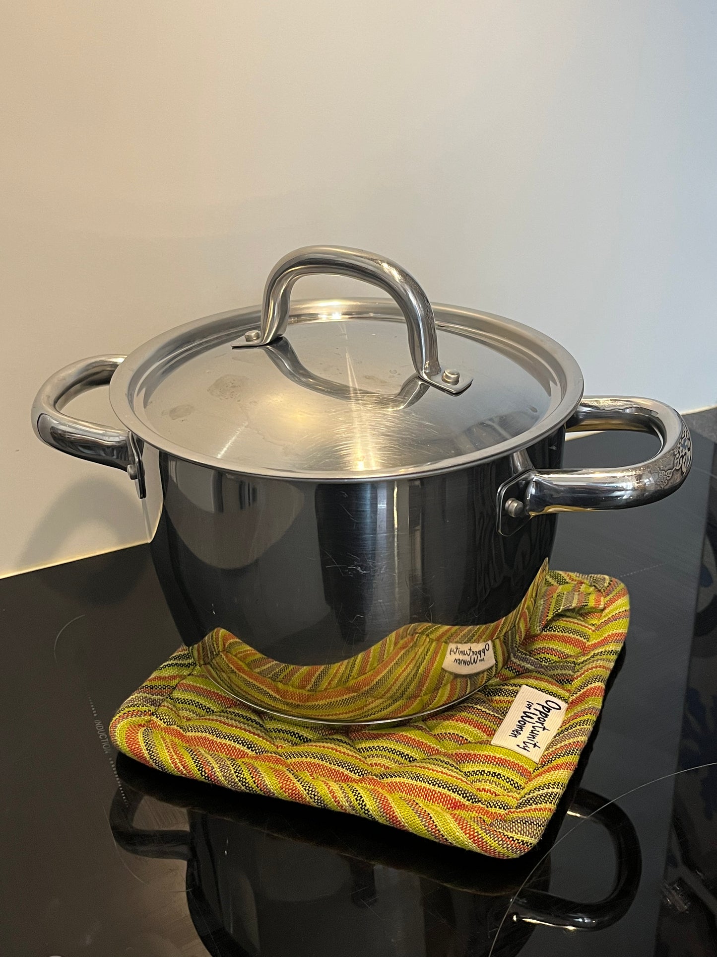 Grüner quadratischer Topflappen mit bunten Linien